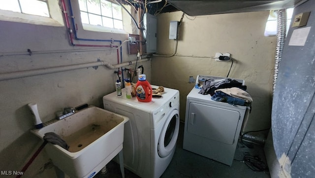 clothes washing area featuring electric panel, sink, and washer and dryer