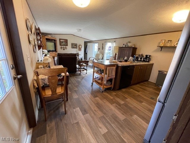 kitchen featuring dark hardwood / wood-style floors, black dishwasher, a textured ceiling, and vaulted ceiling