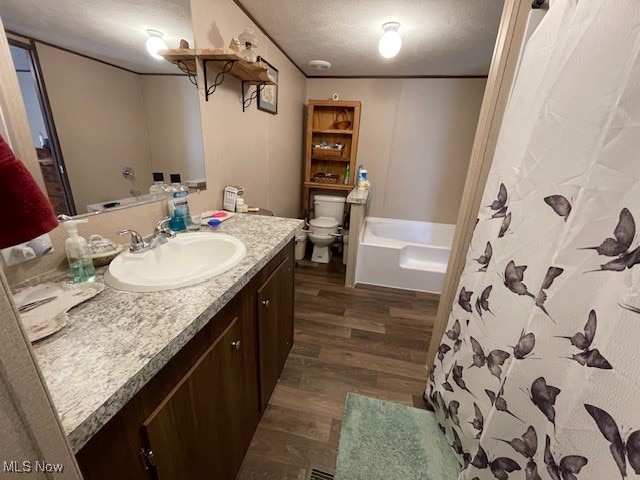 bathroom featuring vanity, hardwood / wood-style floors, toilet, and a textured ceiling