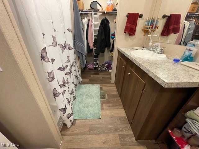 bathroom with vanity, walk in shower, and wood-type flooring