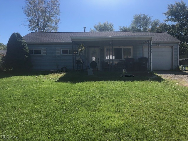 rear view of house featuring a yard and a garage