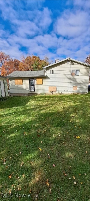 rear view of property featuring a lawn