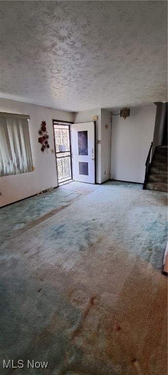 unfurnished living room featuring carpet flooring and a textured ceiling