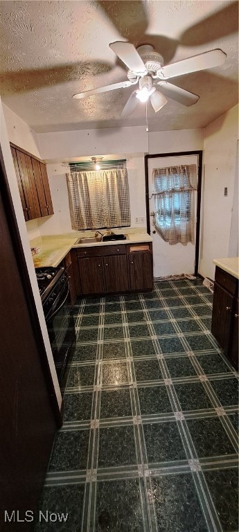 kitchen featuring black gas stove, dark brown cabinets, sink, a textured ceiling, and ceiling fan