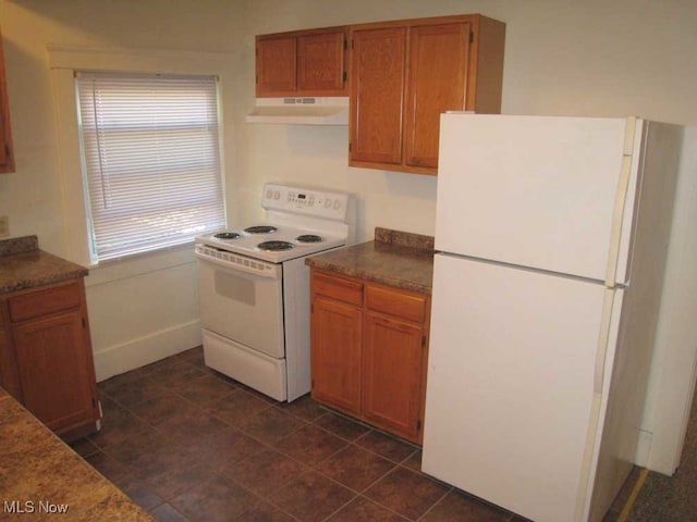 kitchen with white appliances, extractor fan, and dark tile patterned floors