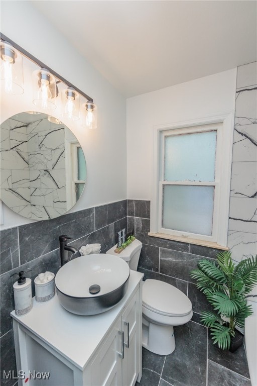 bathroom featuring vanity, toilet, and tile walls