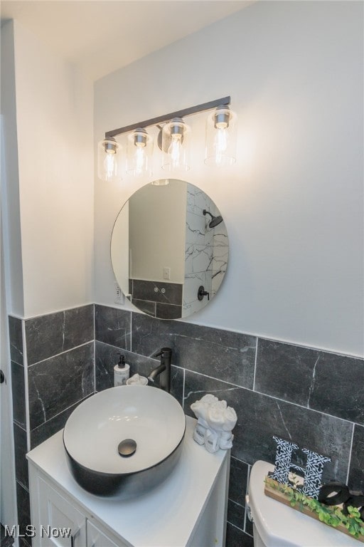 bathroom featuring toilet, vanity, and tile walls