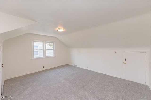 additional living space featuring carpet and vaulted ceiling