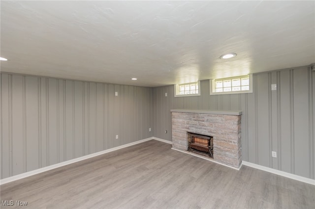 basement with a stone fireplace and light hardwood / wood-style flooring