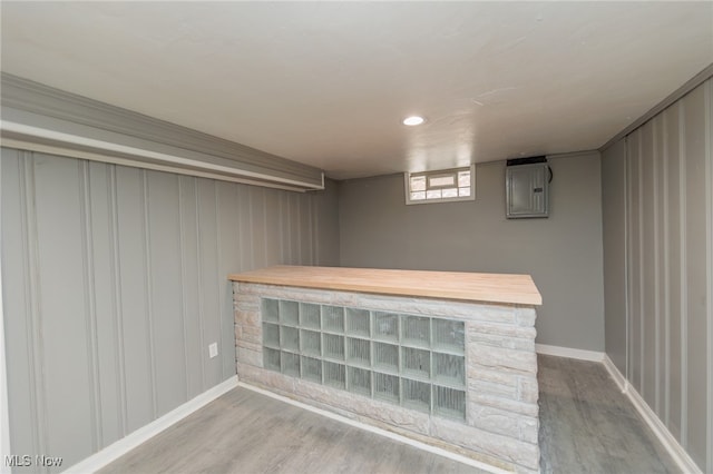 basement with electric panel and light hardwood / wood-style flooring