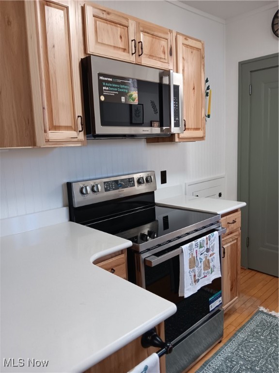 kitchen with appliances with stainless steel finishes, light wood-type flooring, and light brown cabinets