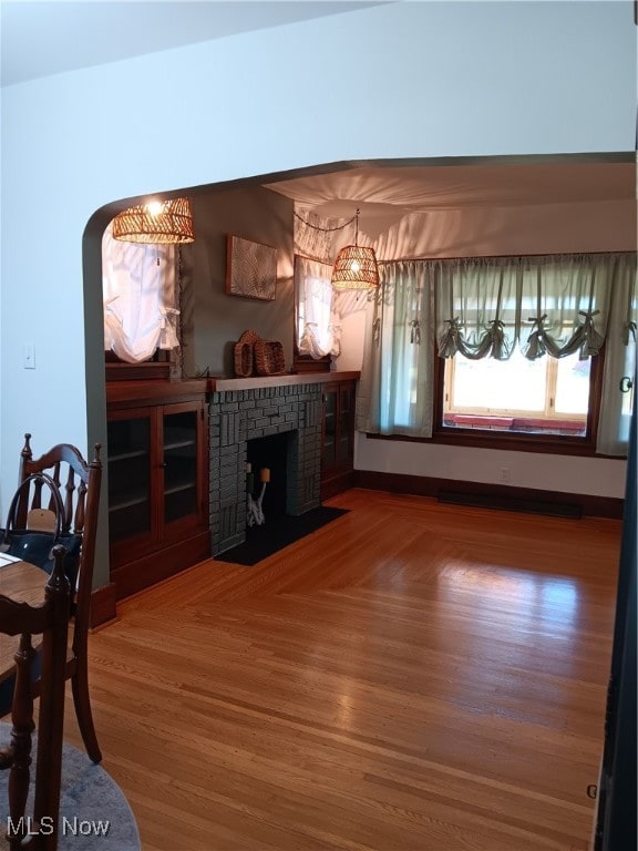 living room with wood-type flooring and a brick fireplace