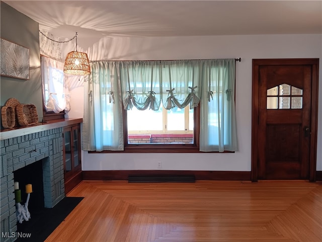 foyer entrance with parquet flooring and a brick fireplace