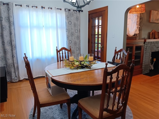 dining space featuring a brick fireplace and light wood-type flooring