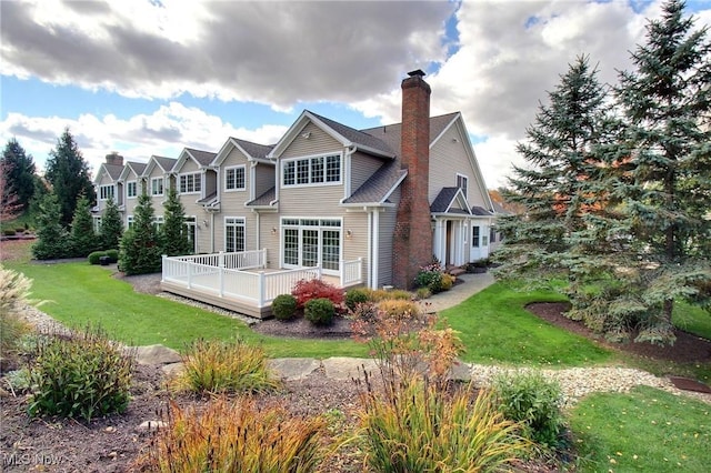 rear view of house featuring a yard and a deck