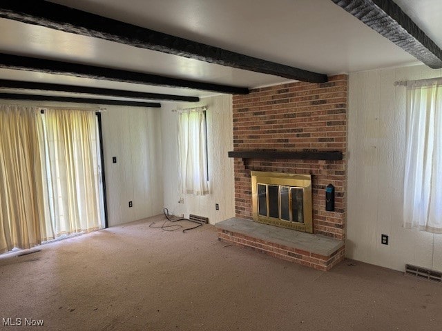 unfurnished living room featuring beam ceiling, carpet, and a brick fireplace