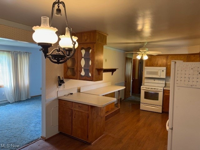 kitchen featuring kitchen peninsula, dark hardwood / wood-style flooring, ceiling fan with notable chandelier, pendant lighting, and white appliances