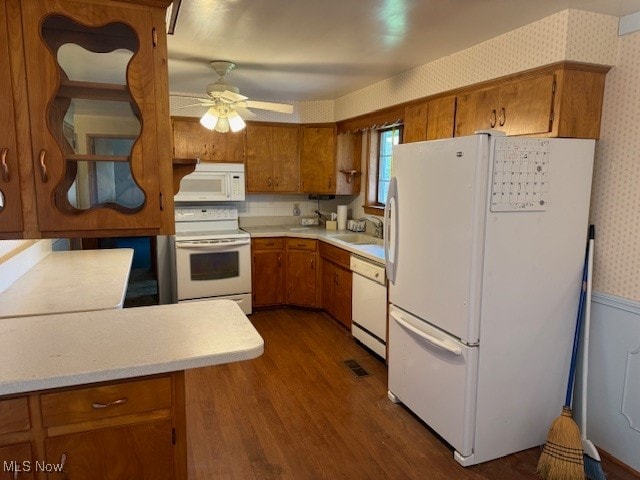 kitchen with dark wood-type flooring, kitchen peninsula, sink, white appliances, and ceiling fan