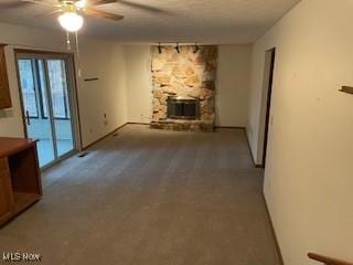 unfurnished living room with rail lighting, ceiling fan, a fireplace, and light carpet