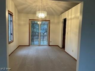 unfurnished room featuring carpet flooring, lofted ceiling, an inviting chandelier, and a healthy amount of sunlight