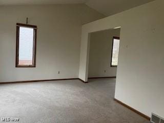 carpeted spare room featuring vaulted ceiling