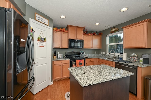 kitchen with black appliances, a center island, light hardwood / wood-style flooring, and a textured ceiling