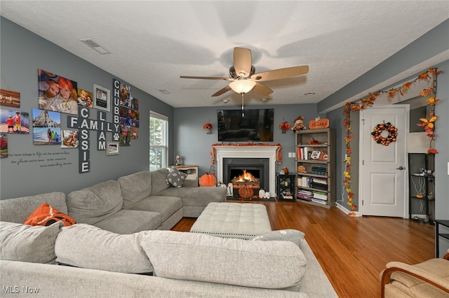 living room with hardwood / wood-style floors, a textured ceiling, and ceiling fan