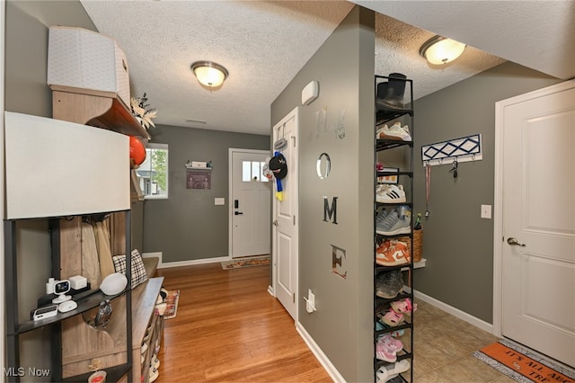 hall with light hardwood / wood-style floors and a textured ceiling