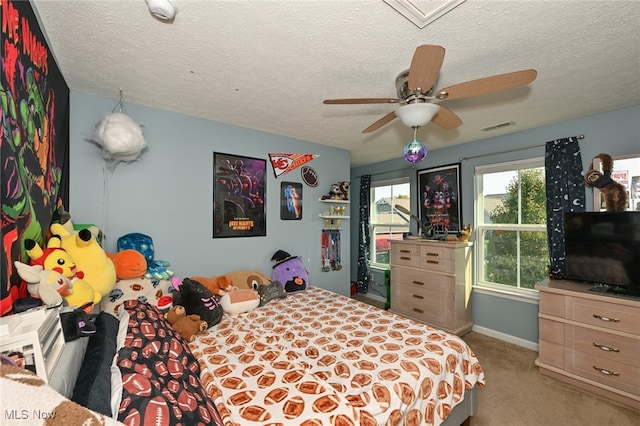 bedroom with a textured ceiling, light colored carpet, and ceiling fan