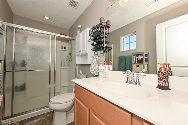 bathroom featuring a textured ceiling, toilet, vanity, an enclosed shower, and tile patterned flooring