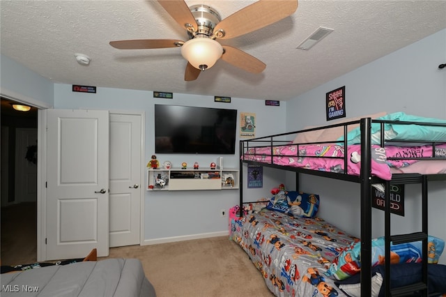 bedroom featuring a textured ceiling, light colored carpet, and ceiling fan