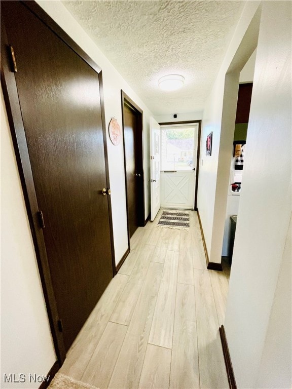 hall with light hardwood / wood-style flooring and a textured ceiling