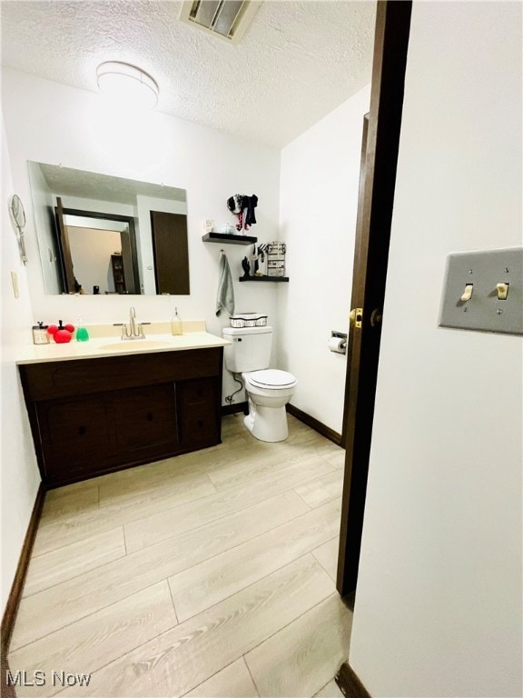 bathroom with vanity, hardwood / wood-style floors, a textured ceiling, and toilet