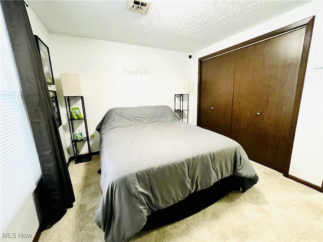 carpeted bedroom featuring a closet and a textured ceiling