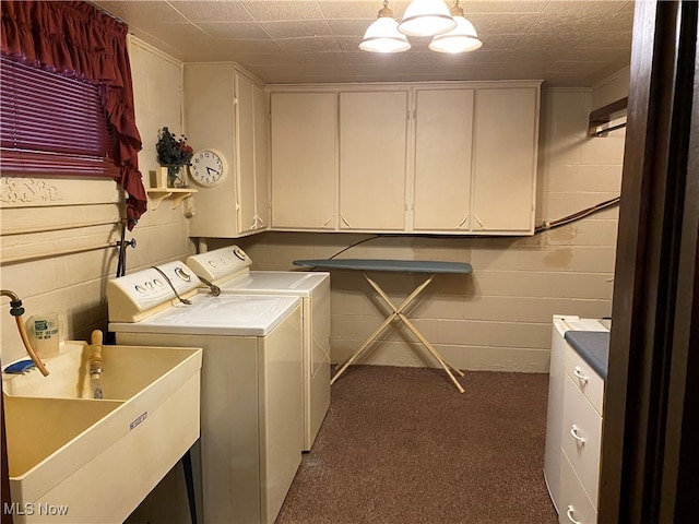 laundry room featuring washing machine and clothes dryer, cabinets, and sink