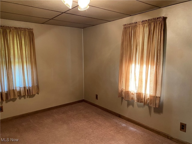 carpeted empty room featuring a paneled ceiling