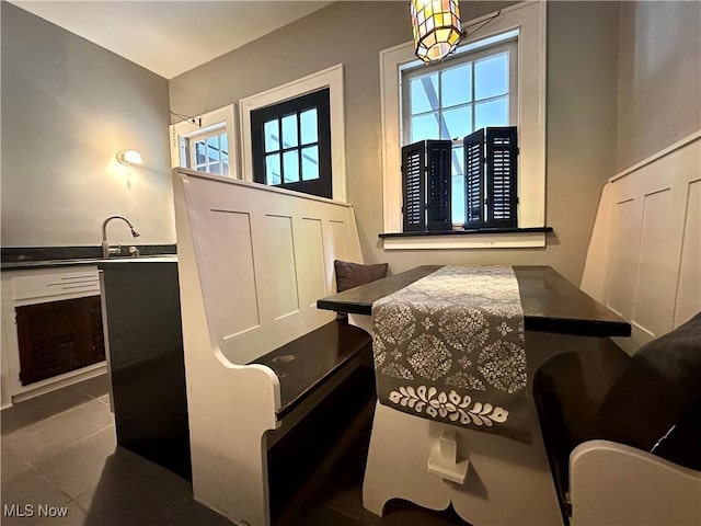 dining room with dark tile patterned floors, sink, and a wealth of natural light