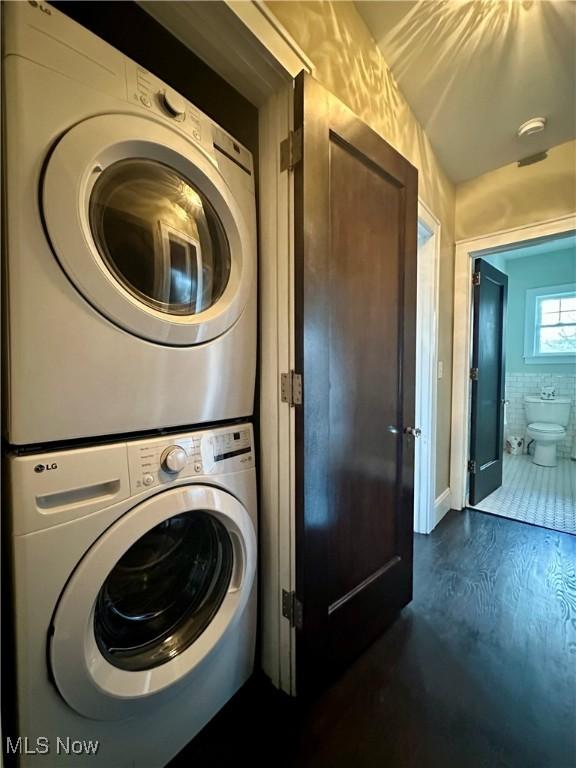 washroom with dark hardwood / wood-style floors and stacked washer / dryer