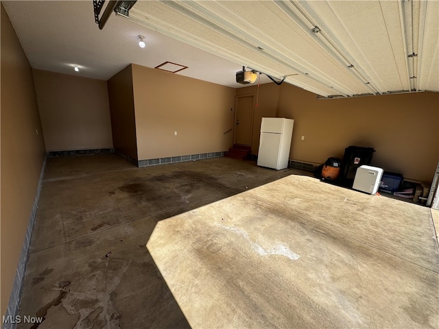 garage with a garage door opener and white fridge