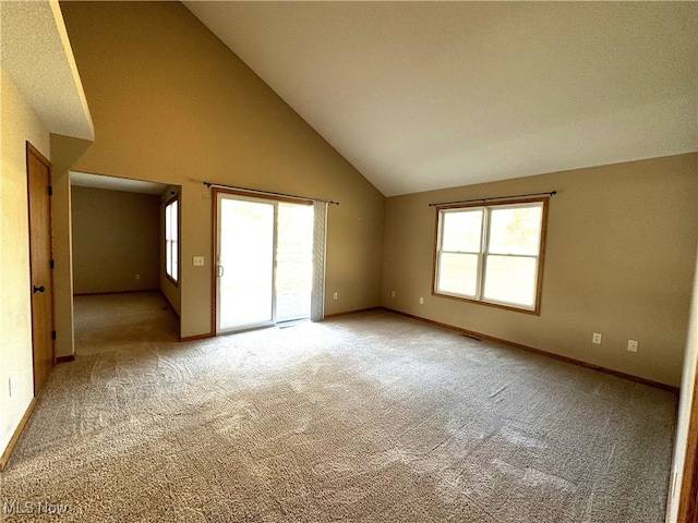 carpeted empty room featuring high vaulted ceiling