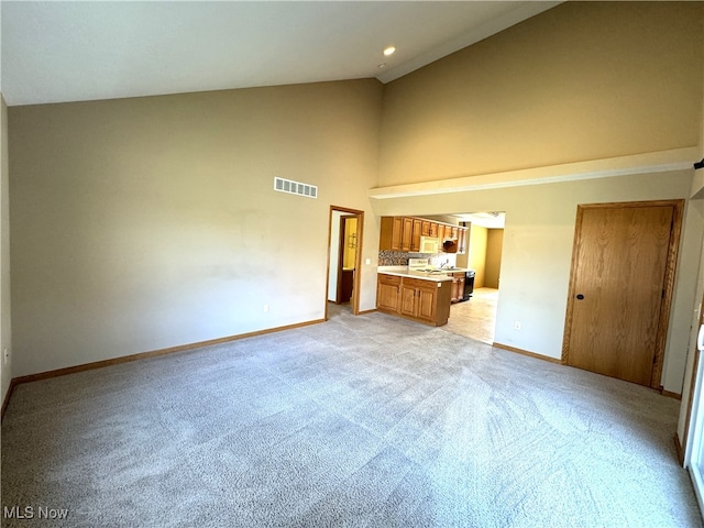 unfurnished living room with light carpet and high vaulted ceiling