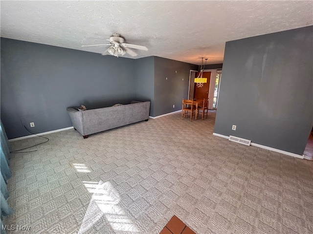 unfurnished living room with ceiling fan and a textured ceiling