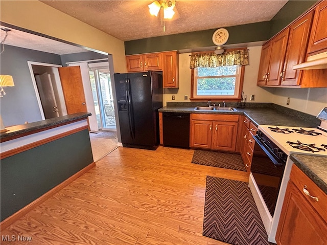 kitchen featuring sink, black appliances, a textured ceiling, and light wood-type flooring