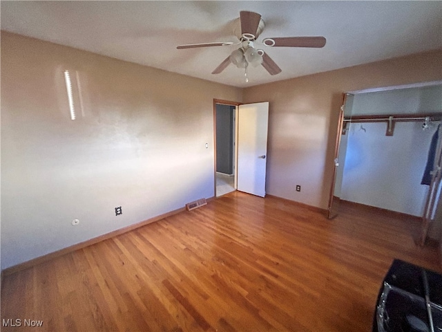 unfurnished bedroom with ceiling fan, a closet, and wood-type flooring