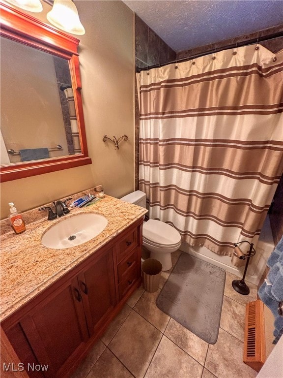 bathroom with tile patterned floors, vanity, a textured ceiling, and toilet