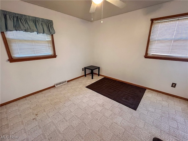 carpeted empty room with a wealth of natural light and ceiling fan