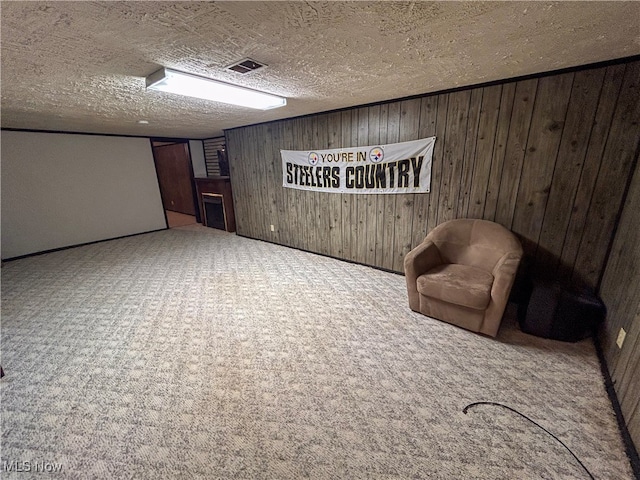 unfurnished room with carpet flooring, a textured ceiling, and wooden walls