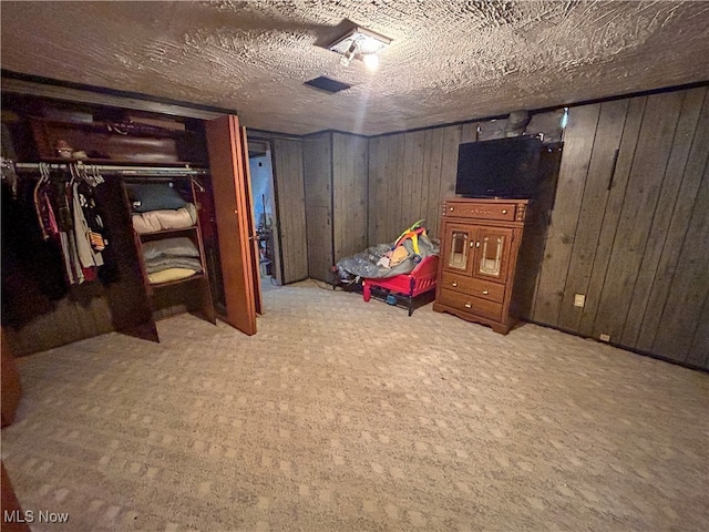 unfurnished bedroom featuring wood walls, a textured ceiling, and light carpet