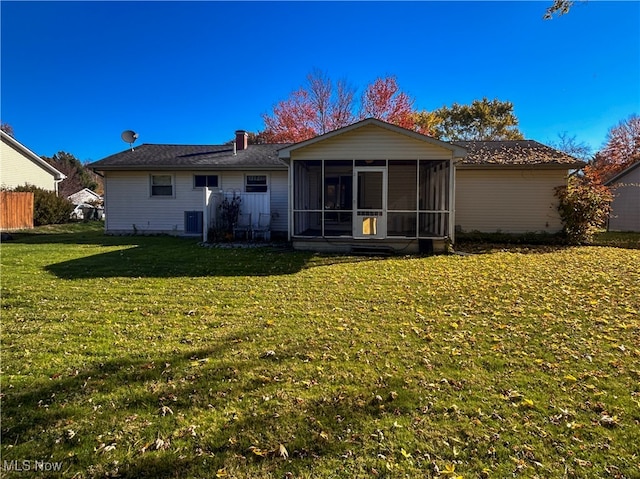 rear view of house featuring a sunroom, central AC unit, and a lawn