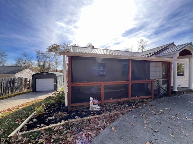 view of side of home with a sunroom and an outbuilding